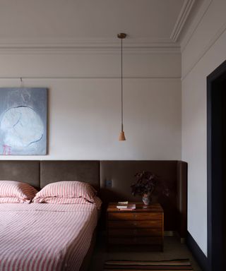 clay colored bedroom with red striped bedding and extended dark brown headboard