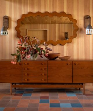 tiled entryway with wood paneling and a wavy walnut mirror
